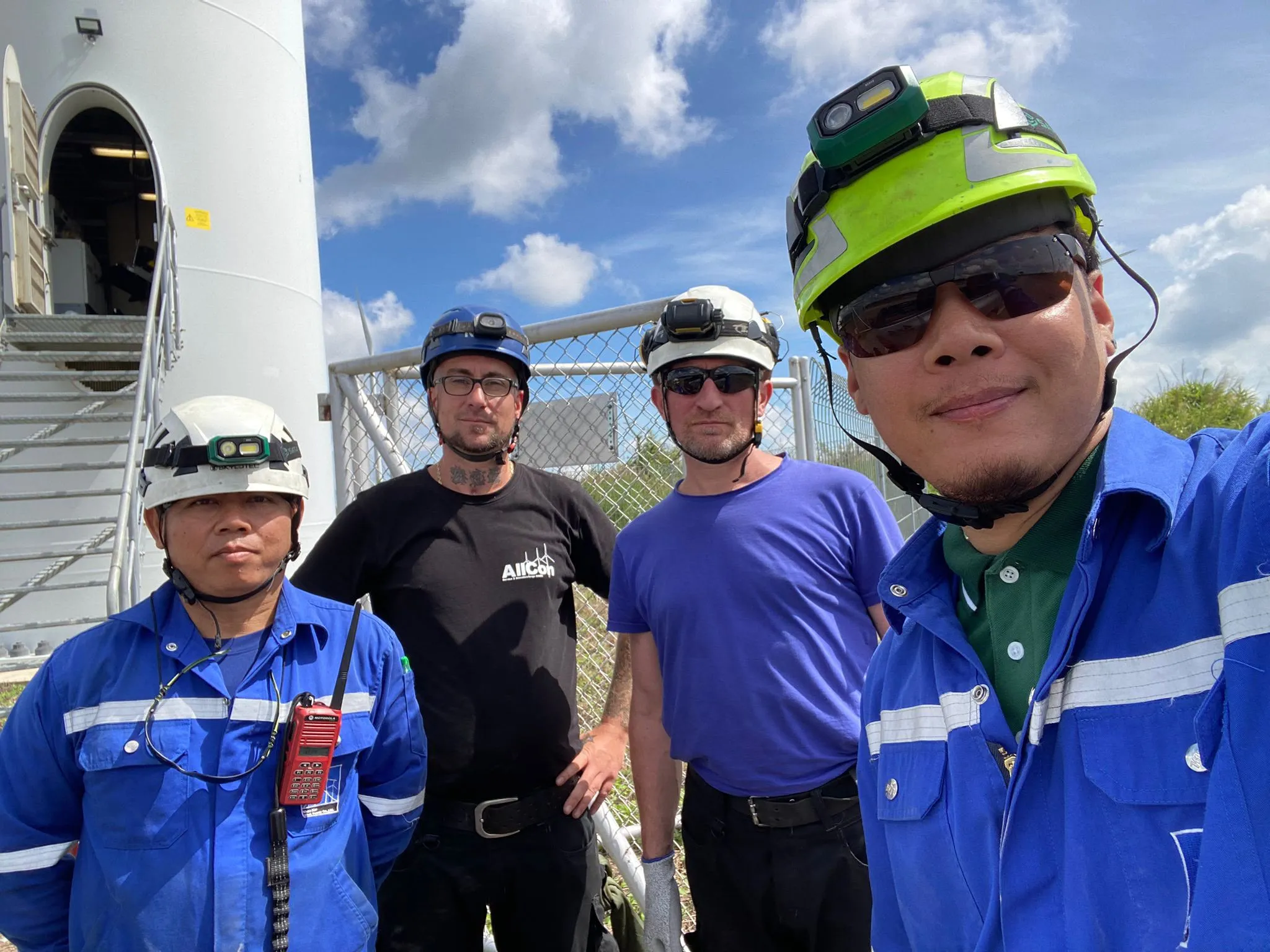 Vierköpfiges AllCon-Team am Turmfuß einer Windturbine