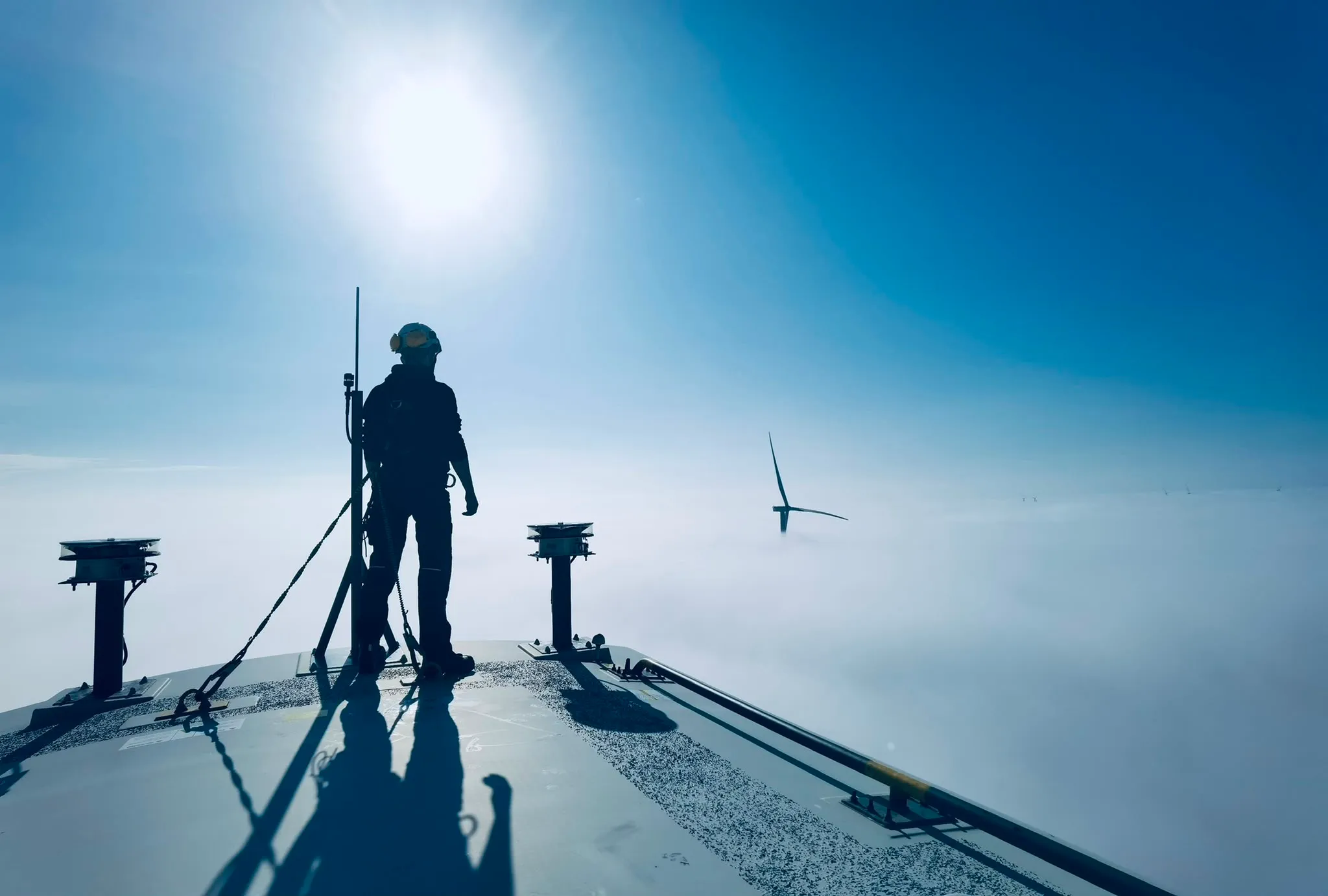 Techniker auf der Gondel einer Windturbine über den Wolken